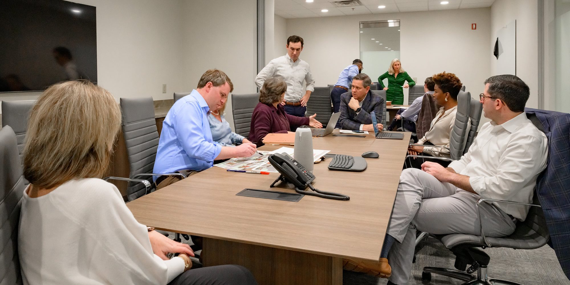 Team members engage in a meeting, reviewing documents and discussing ideas at a conference table.